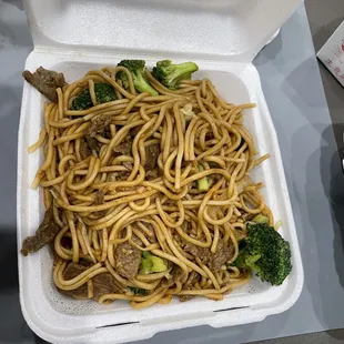 a take out box of noodles and broccoli