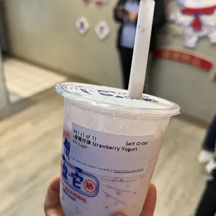 a hand holding a plastic cup with a straw