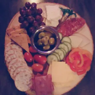 a platter of cheese, crackers, olives, and tomatoes