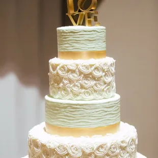 White and mint colored cake with gold ribbon