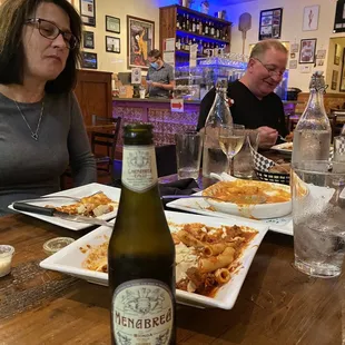 a woman sitting at a table with a bottle of pizzeria