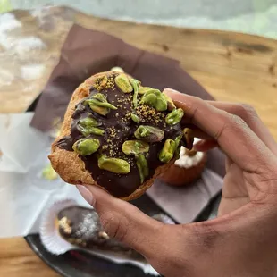 a person holding a chocolate covered pastry