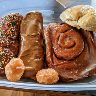 Two maple bars, one with sprinkles, raspberry scone, cinnamon roll, and a couple donut holes.