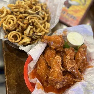 a plate of chicken wings and a basket of onion rings
