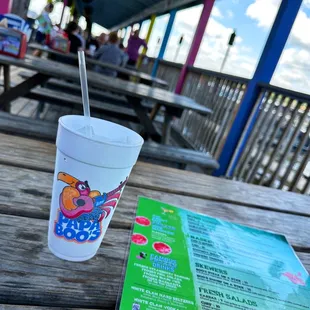 a drink and menu on a picnic table