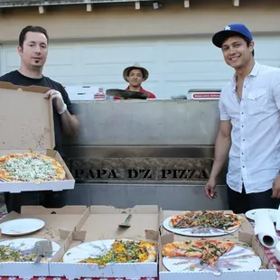 two men holding pizzas