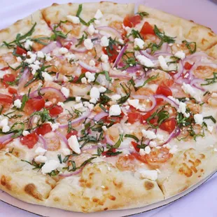 a pizza with tomatoes, onions, and feta cheese