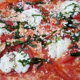 a pizza with mozzarella, tomatoes, and basil