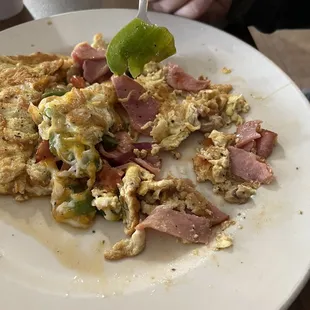 Denver omelette with chucks of raw green bell pepper and sliced lunch meat.