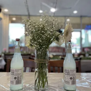 a vase of flowers and bottles of soda