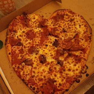 Heart shaped pizza with pepperoni and cheesesteak, barely any toppings for having paid an additional price.