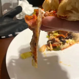 A paper thin slice of pizza composed of toppings with a crust. At 8 pm on a Thursday.