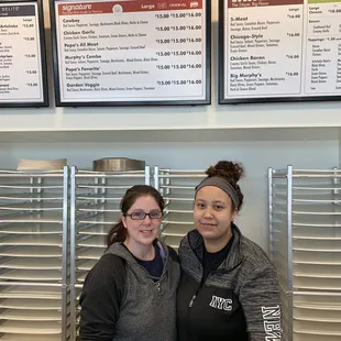 two women standing in front of a menu