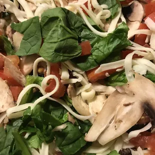 a pizza with spinach, mushrooms, tomatoes, and mushrooms