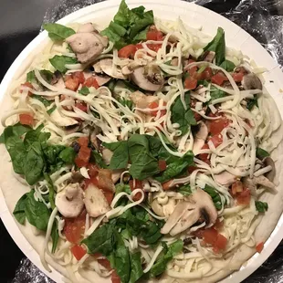 a pizza with spinach and mushrooms