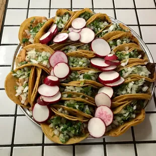 a plate of tacos with radishes