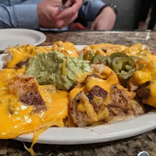 a plate of nachos with cheese and guacamole