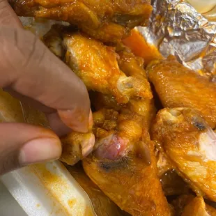 a hand grabbing a piece of chicken wings