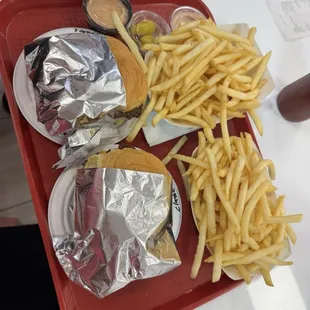 Two different smash burgers with fries and two different kind of dipping sauce.