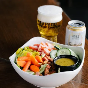 a bowl of salad and a can of beer