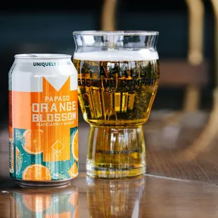 a glass of beer and a can of orange blossom