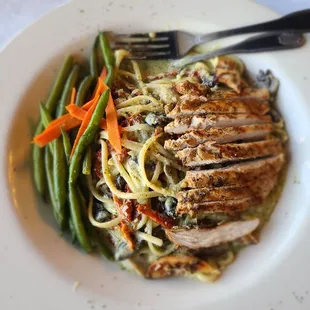 a plate of pasta with chicken and green beans