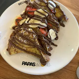 a plate of french toast with bananas and strawberries
