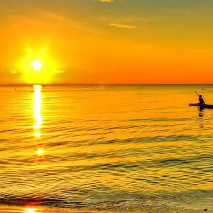 a man in a boat on the water at sunset