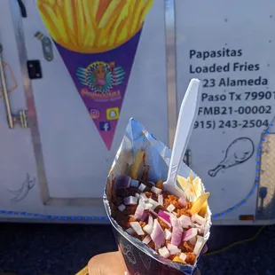 a hand holding a cone of fries