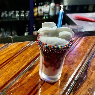 an ice cream sundae with sprinkles and a blue candle