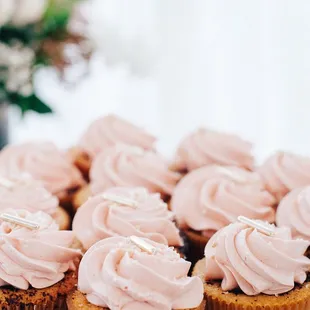 a plate of cupcakes with pink frosting