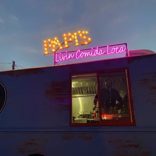 a food truck with a neon sign above it