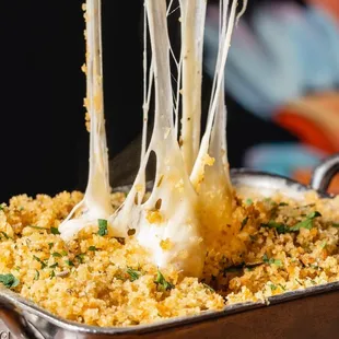 a piece of cheese being pulled out of a casserole dish