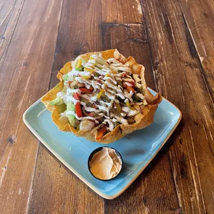 Fajita Taco Ensalada: fried flour shell, romaine, queso fresco, tomato, fajita peppers &amp; onions, avocado, crema, dressing; add a protein!