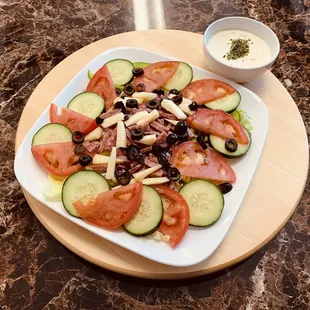Antipasto salad with cucumbers, tomatoes, lettuce, onion, green peppers, pepperocini and feta cheese.
