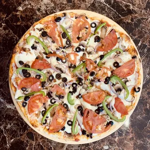 Delicious veggie pizza with fresh ingredients like mushroom, black olives, onions, green peppers and tomatoes.