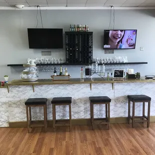 Bar area with two TVs featuring teas, juices, sodas, beer, wine and cocktails