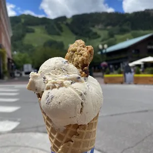 Peanut butter chip ice cream in a waffle cone with a mini oatmeal chocolate chip cookie.