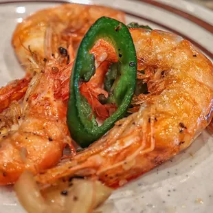 a plate of cooked shrimp with a jalapeno pepper