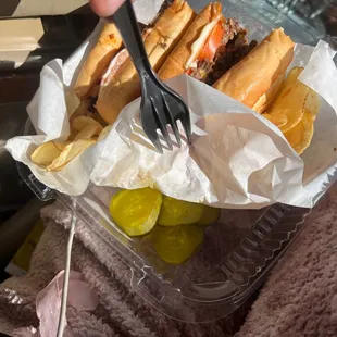 a person eating a sandwich and pickles