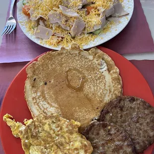 Chef salad and breakfast platter with eggs, sausage and pancakes.