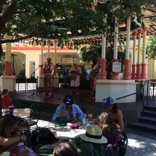 a group of people sitting at a table under a tree