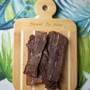a wooden cutting board with two pieces of meat on it