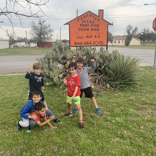 a group of children posing in front of a sign