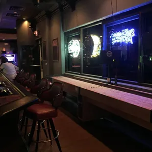 a bar with a neon clock in the window