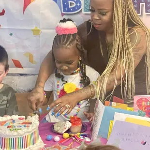 Mom and birthday girl cutting the cake