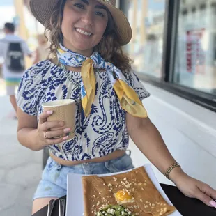 a woman sitting at a table with a plate of food and a cup of coffee