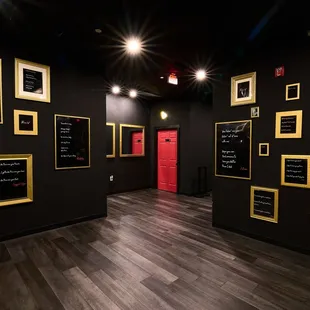 black walls with gold frames and a red door
