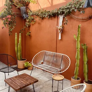 a patio with chairs, tables and cacti