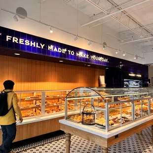 a woman walking past a display of pastries